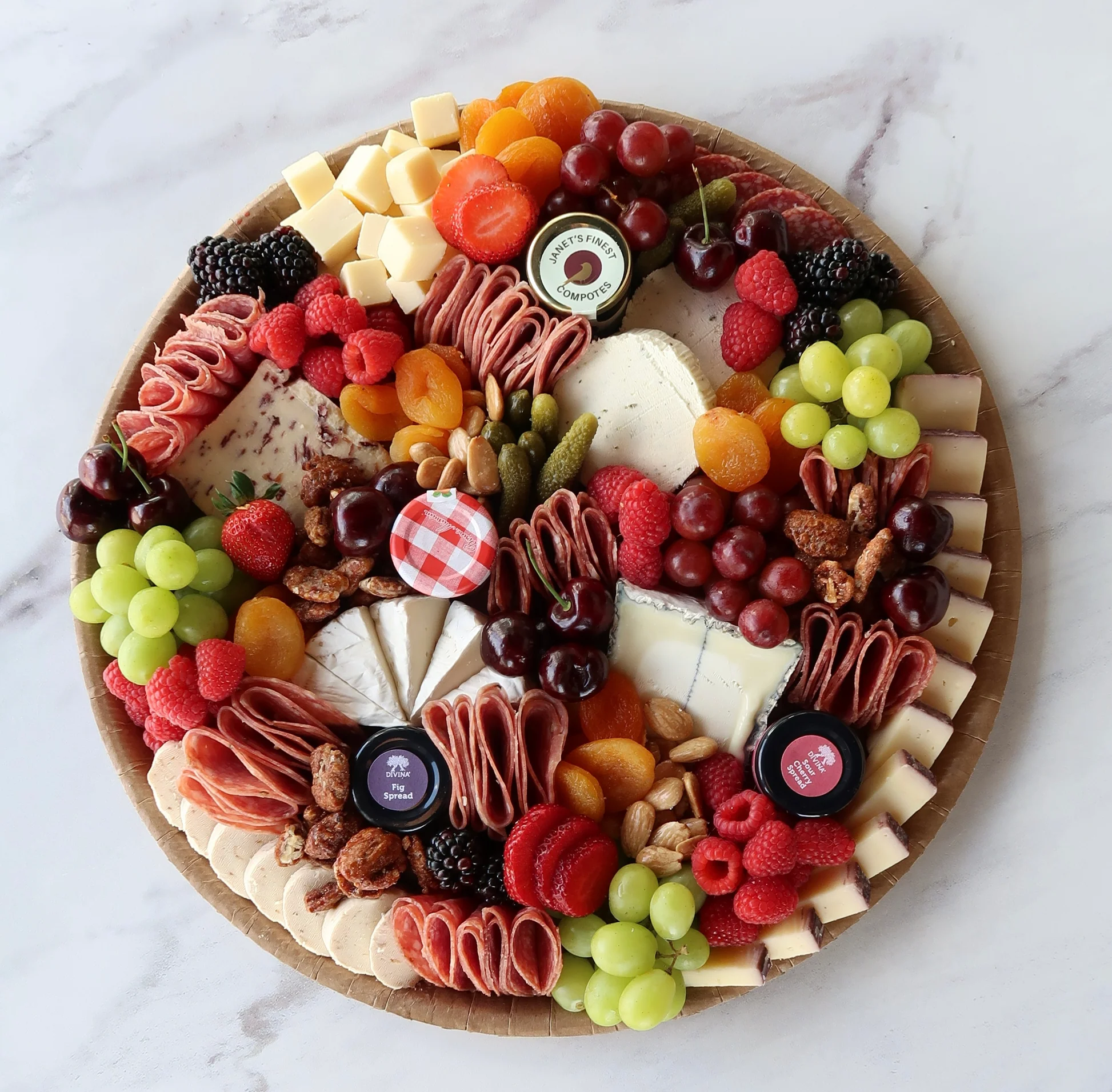 Charcuterie board with cheese, berries, grapes, and fig spread